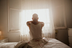 Persona con cabeza rapada mirando por la ventana en un ambiente tranquilo