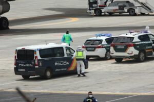 Polic&iacute;as nacionales, guardias civiles y militares de la UME vestidos con monos EPI y mascarillas coordinan a los viajeros evacuados del crucero MV Hondius, en el aeropuerto de Tenerife Sur (Foto: &Aacute;lex Rosa)