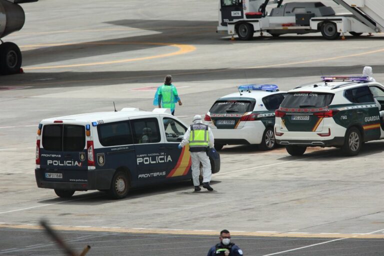 Polic&iacute;as nacionales, guardias civiles y militares de la UME vestidos con monos EPI y mascarillas coordinan a los viajeros evacuados del crucero MV Hondius, en el aeropuerto de Tenerife Sur (Foto: &Aacute;lex Rosa)