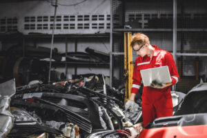 Trabajador en un desguace revisando piezas de autom&oacute;viles usados